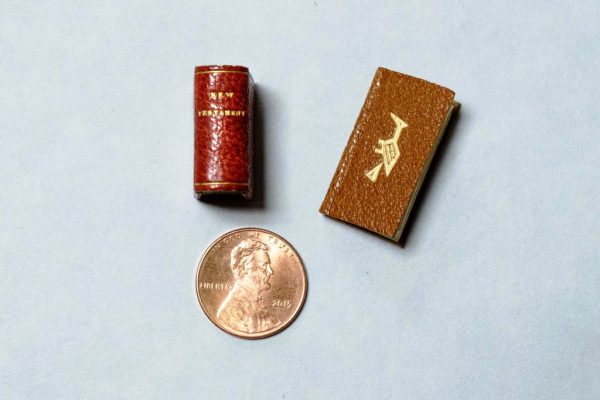 Kalamazoo College's miniature copy of the New Testament along with another miniature book called Bird Word sized beside a penny to show their size. 