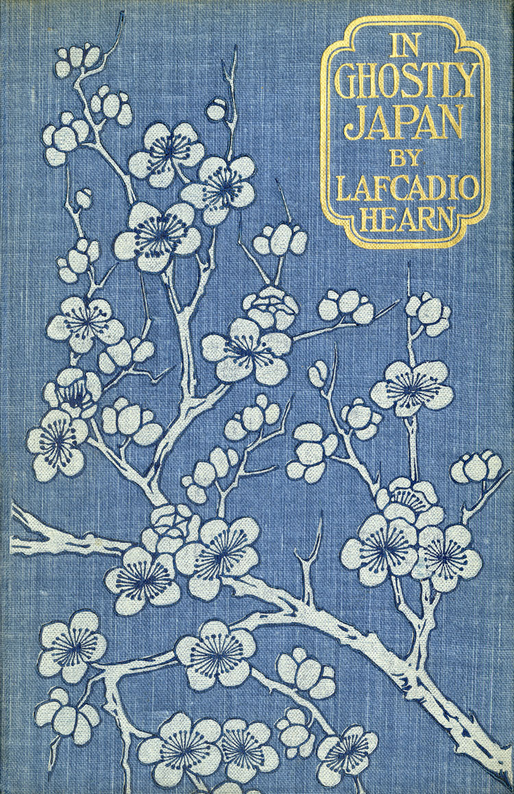The blue cloth cover of the book, In Ghostly Japan by Lafcadio Hearns. It is decorated with white blossoms.